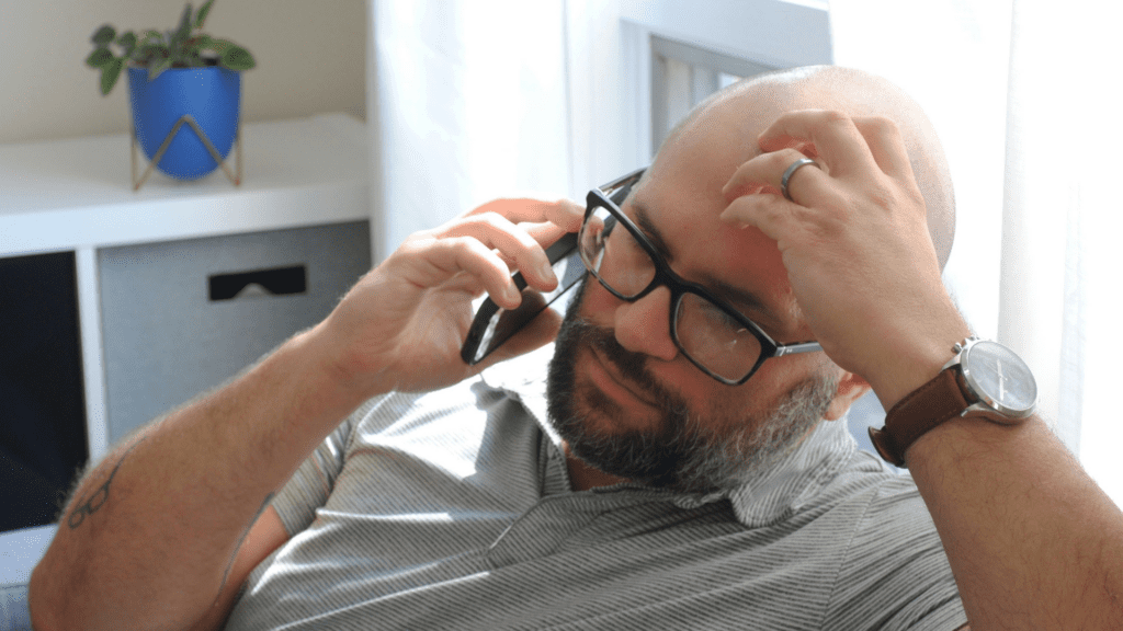 A middle aged, bald male on the phone to Cancer Council NSW's Cancer Information and Information line, 13 11 20.