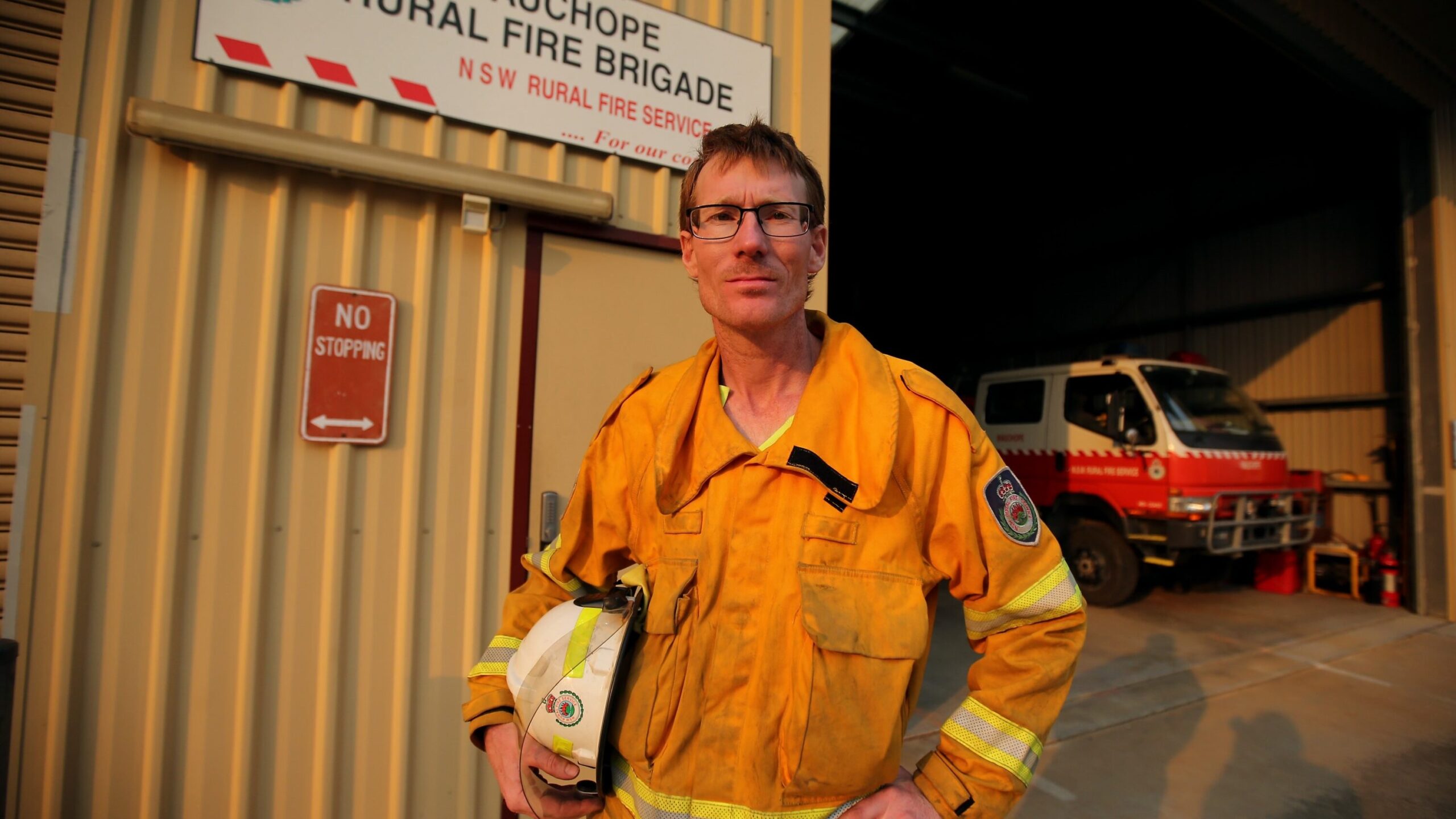 Ryan in front of the Wauchope Rural Fire Brigade, holding his helmet.