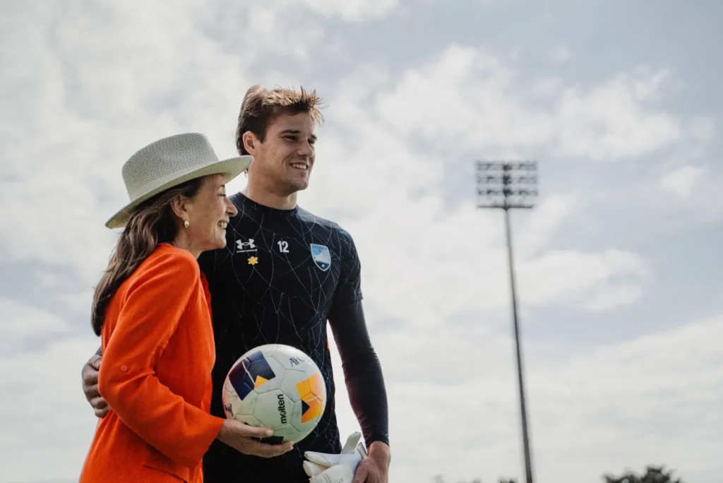 Rossana and Harrison standing on the field. Rossana is holding a soccer ball.