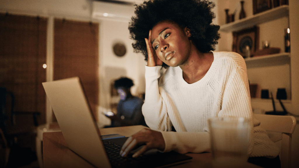 Woman on the computer looking at her finances realising the impact of a cancer diagnosis.