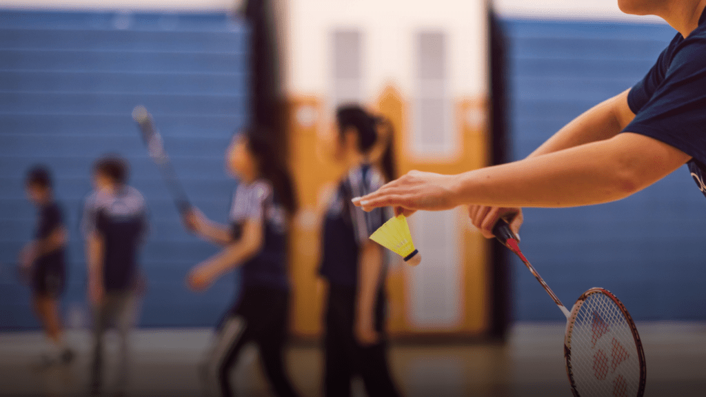 Here's a photo of a group of young people playing badminton, an indoor racquet sport.